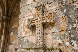 Croix templière en pierre sculptée sur le mur d'une chapelle médiévale, symbole historique des Templiers