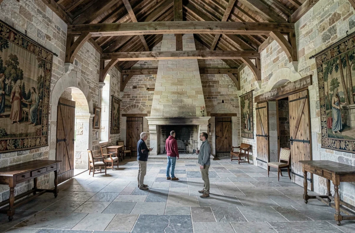 Trois joueurs adultes explorant une salle voûtée en pierre authentique lors de l'escape game au Château de Gramont en Occitanie