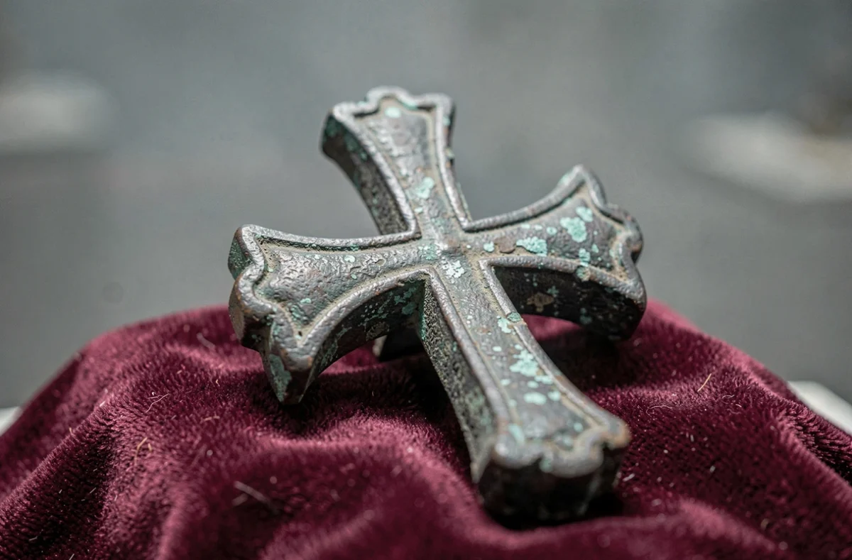 Gros plan d'une croix templière en fer ancien sur tissu bordeaux, artefact historique des Templiers