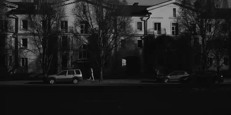 grayscale photo of cars parked near building